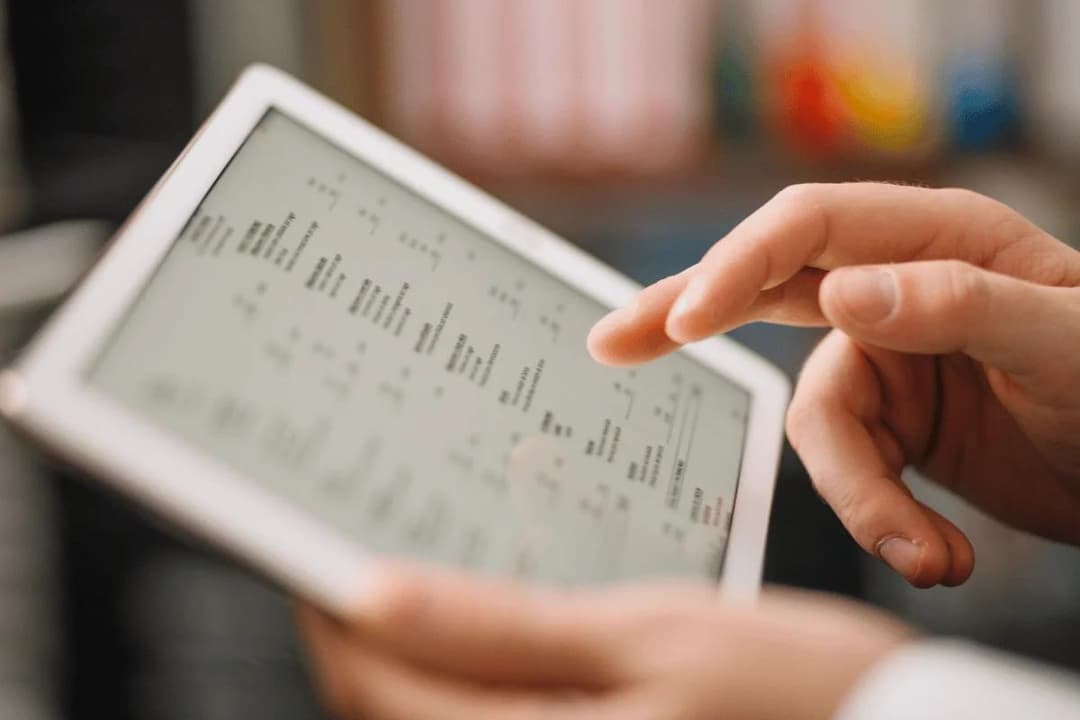 A person using a tablet, interacting with a digital interface displaying various data and information.