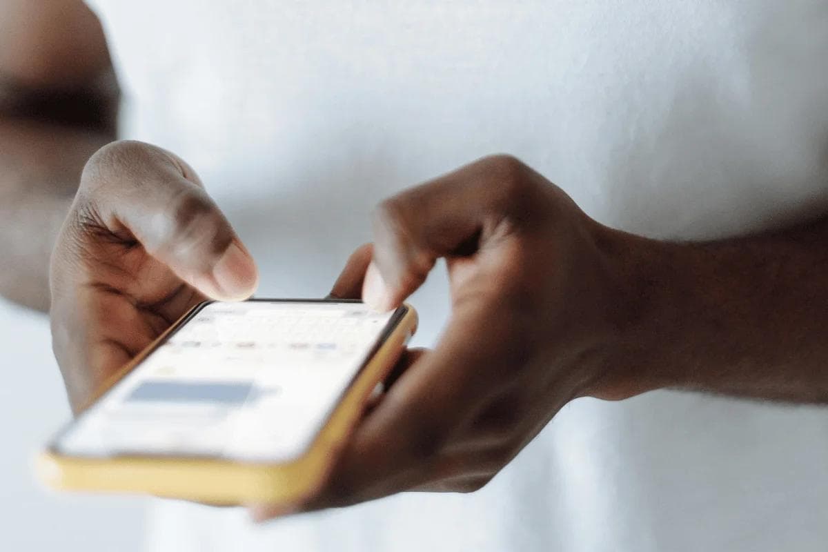 Hands holding phone while typing a message on screen.