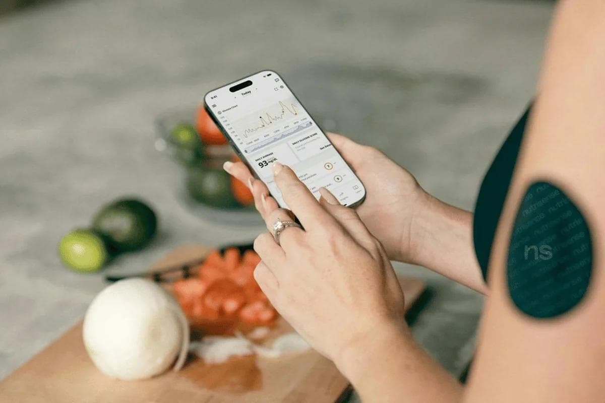 Woman using fitness app on phone in kitchen setting.