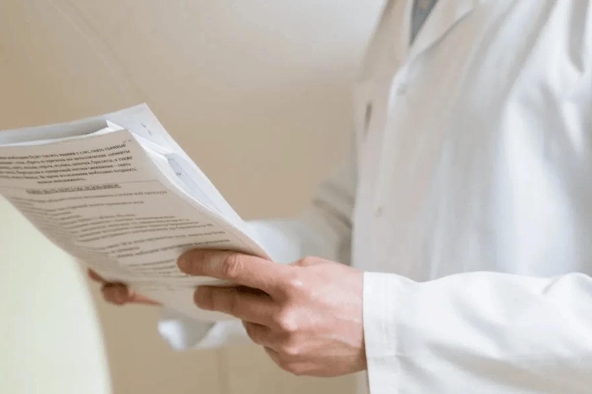 Doctor in white coat reviewing medical documents comparing fee for service vs value based care payment models.