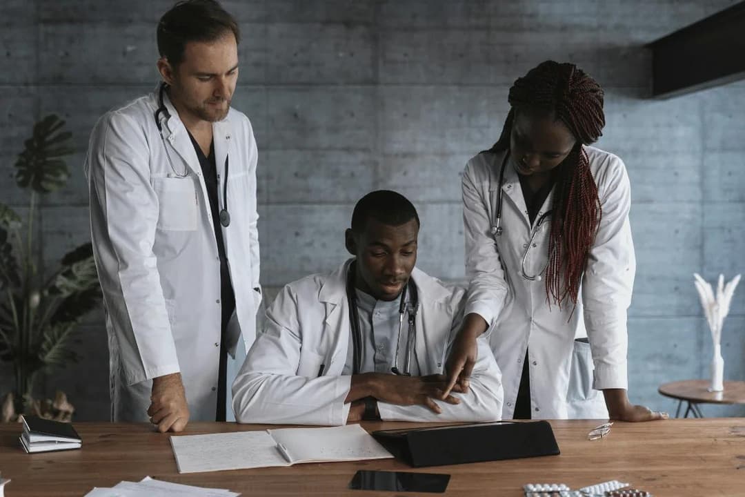 Three doctors review patient notes together, emphasizing medical teamwork and collaborative healthcare planning.